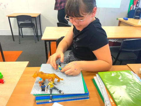 girl drawing pictured with figurines in a stop motion film class